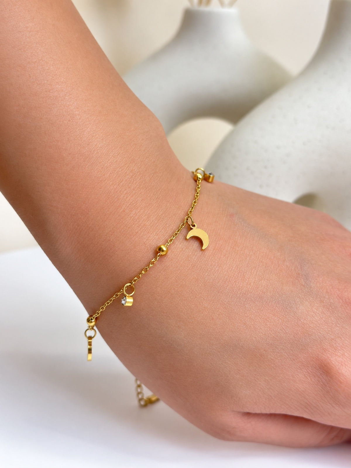 Paired Altheira Bracelet in gold-tone, worn on the wrist with a crescent moon charm, beads and extension chain