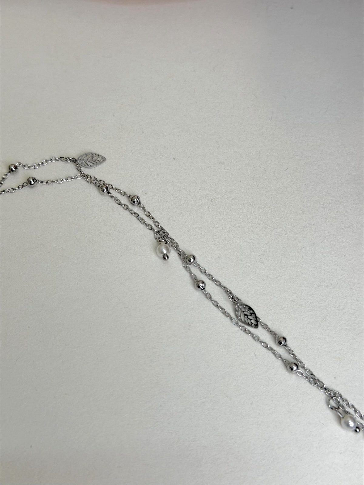 Paired Aurevia Anklet in silver-tone, laid flat showing layered beaded chains with leaf charms