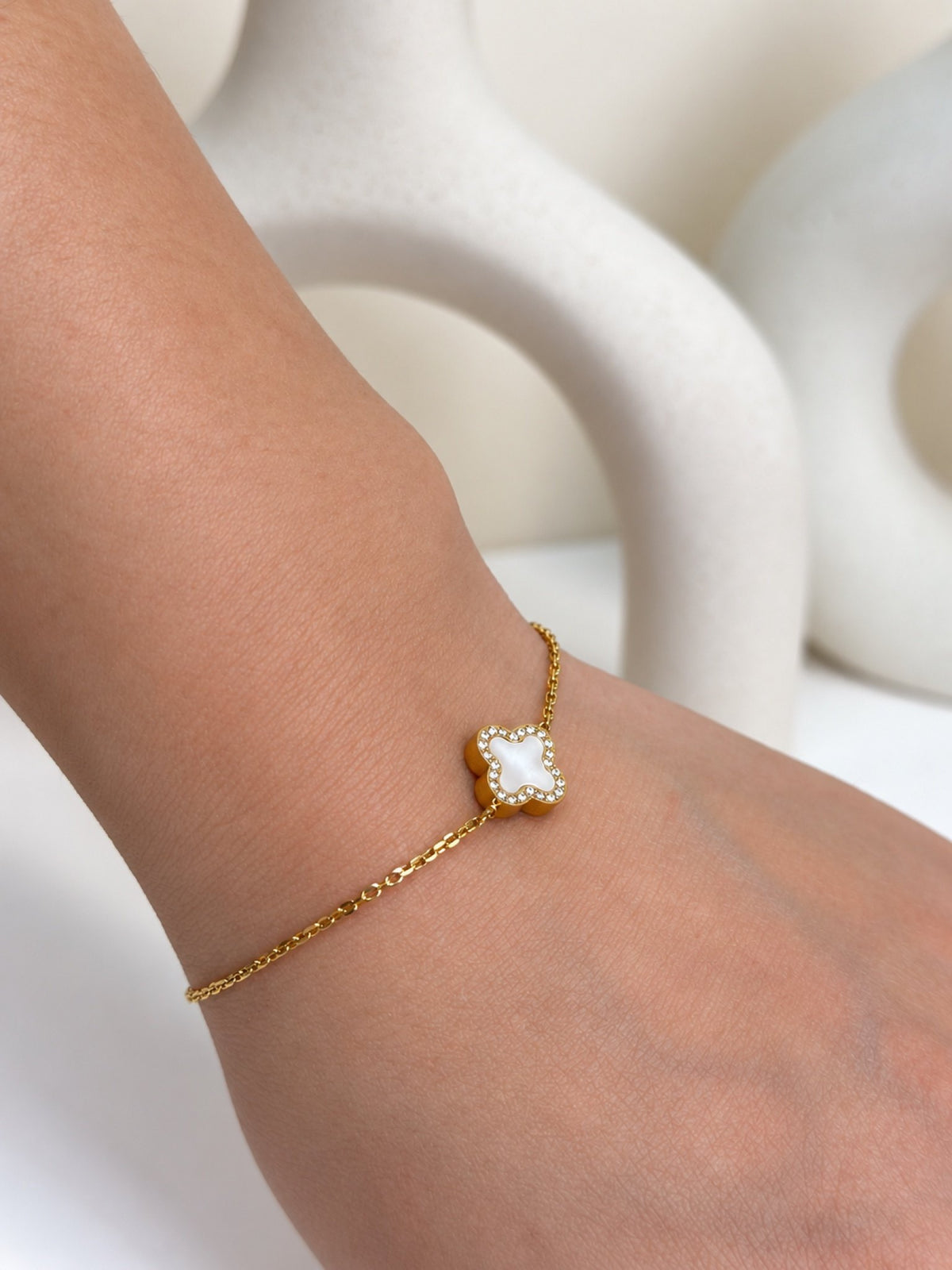 Paired Clover Étoile Bracelet in gold-tone, close view on the wrist showing the white clover charm with sparkling edge