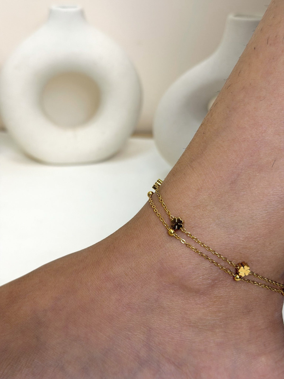 Paired Elara Anklet in gold-tone, close view on the ankle showing double chains and flower-shaped charms