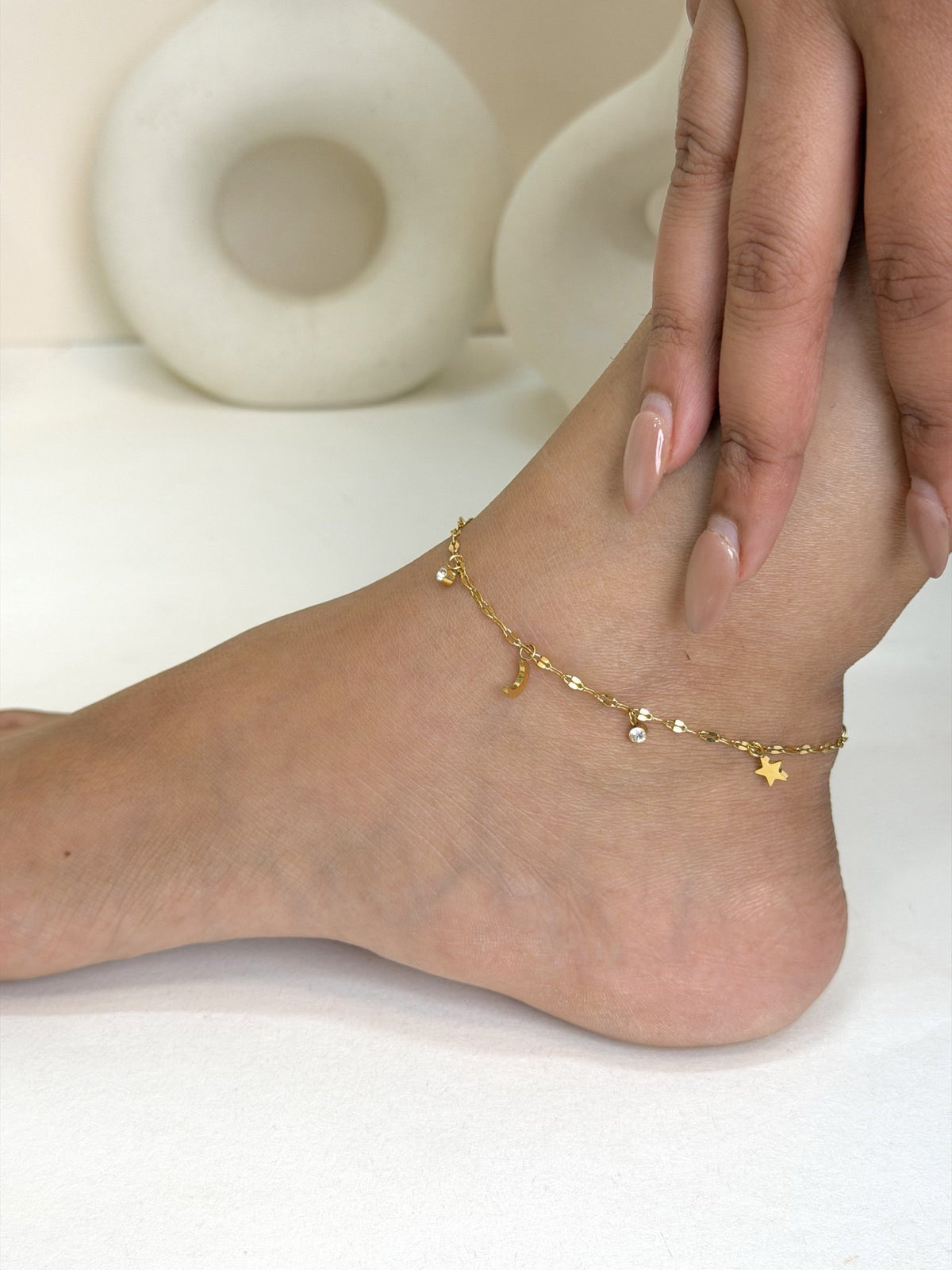 Paired Lilia Anklet in gold-tone, worn on the foot and ankle with a fine chain and small star charms