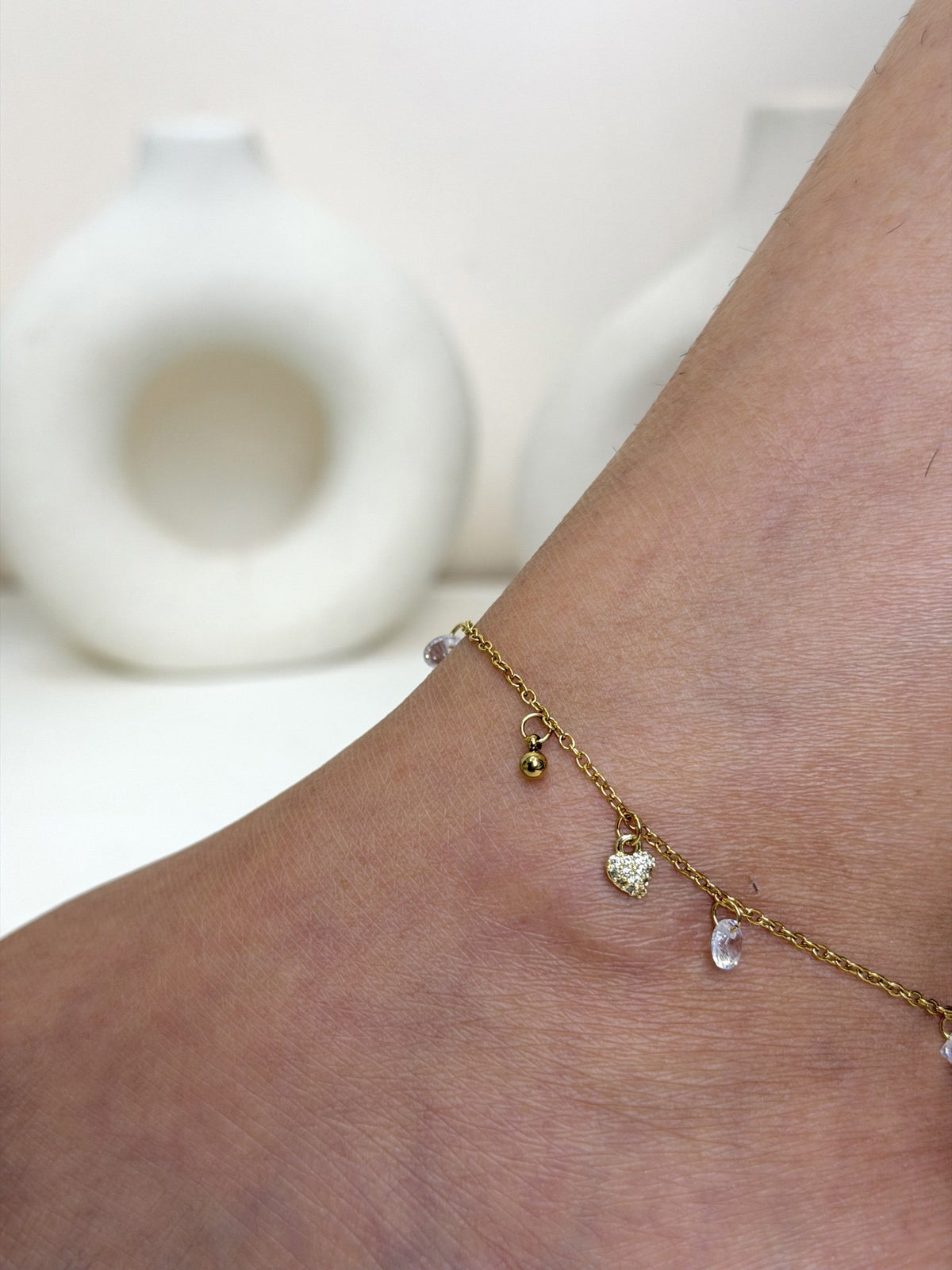 Paired Lunelle Anklet in gold-tone, close-up on the ankle with heart charm, bead and clear drop stones