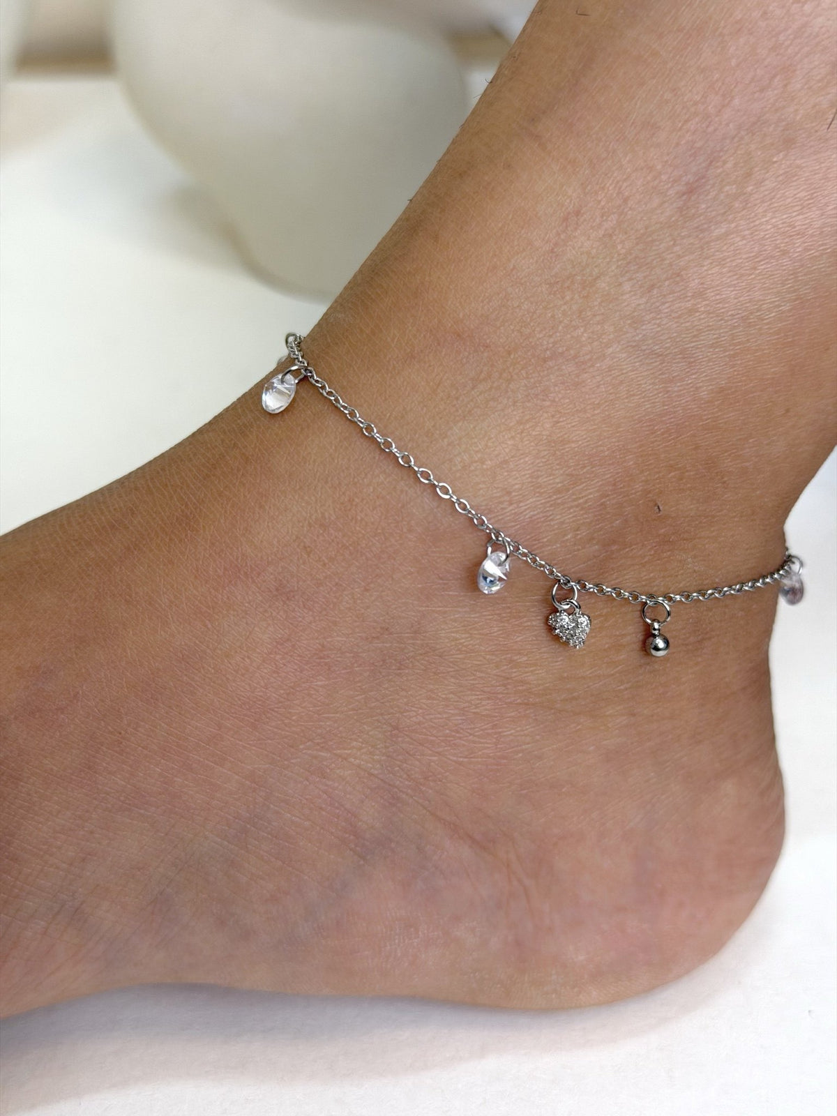 Paired Lunelle Anklet in silver-tone, close view on the ankle with clear drop stones and a heart charm