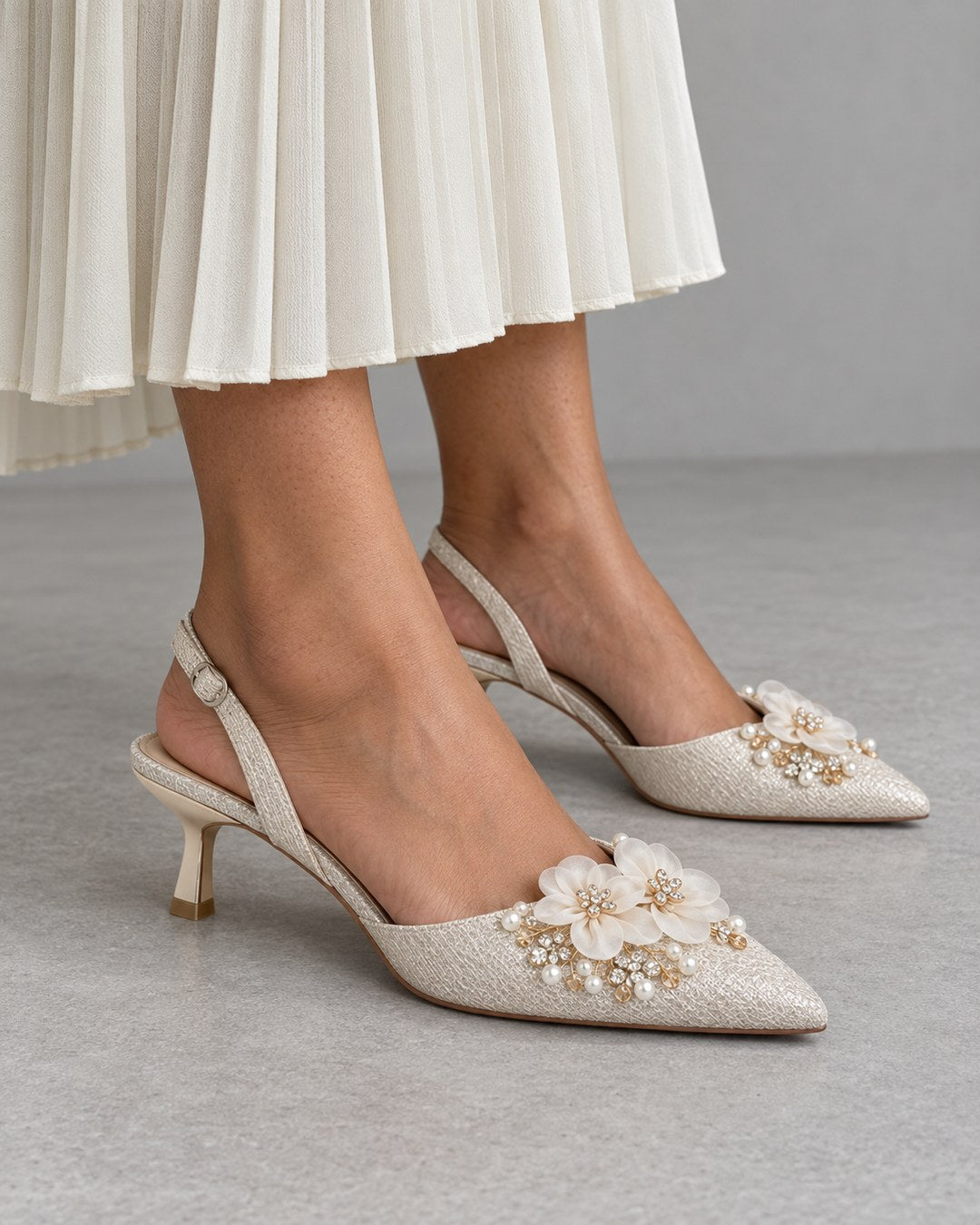 Paired Senorita Bloom Heel: ivory floral slingback kitten heels worn with a pleated skirt, for the wedding guest edit