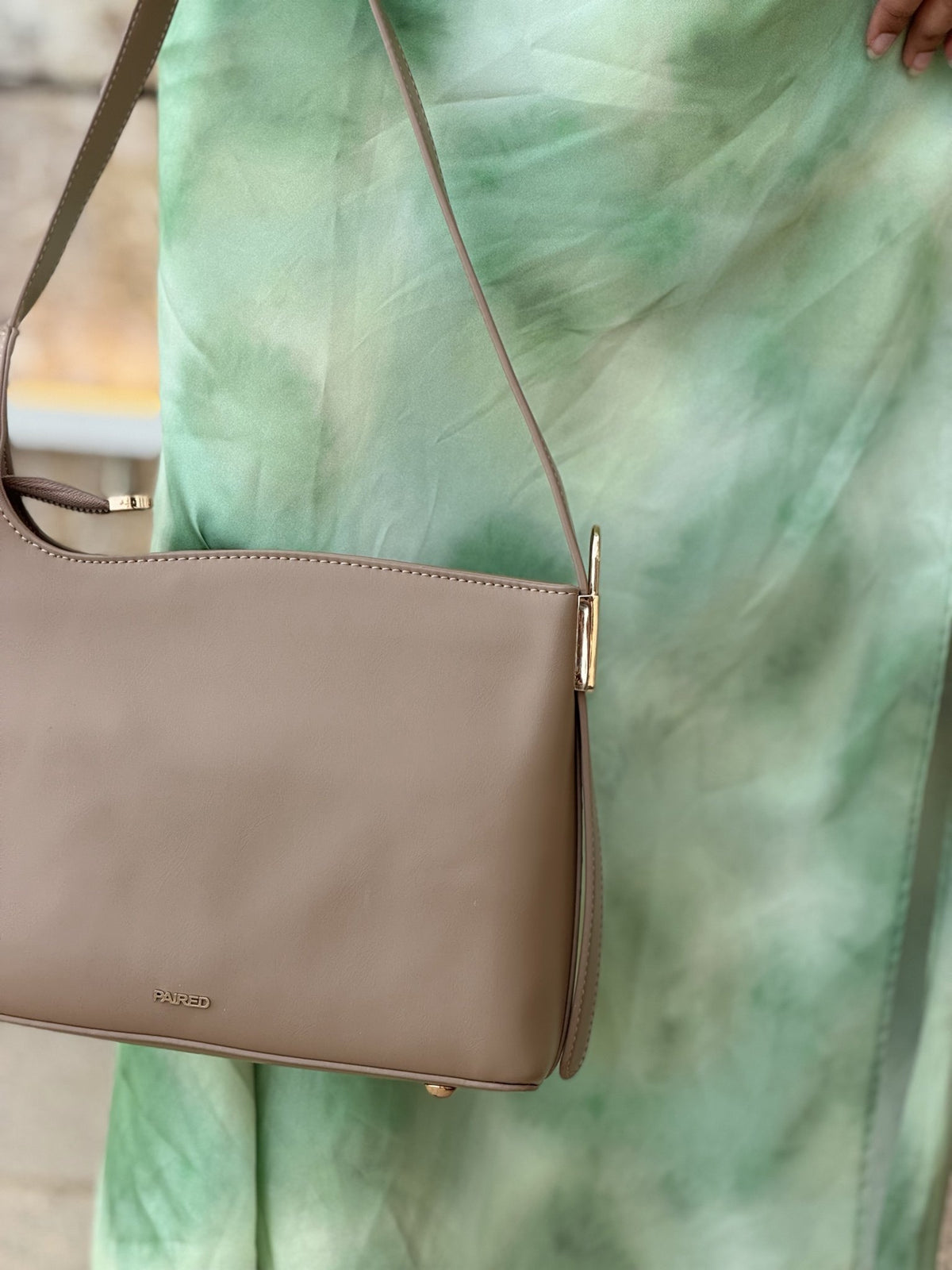 Paired Oriana Gold-Lock Bag in taupe apricot, worn on the shoulder with a long strap against a green satin skirt