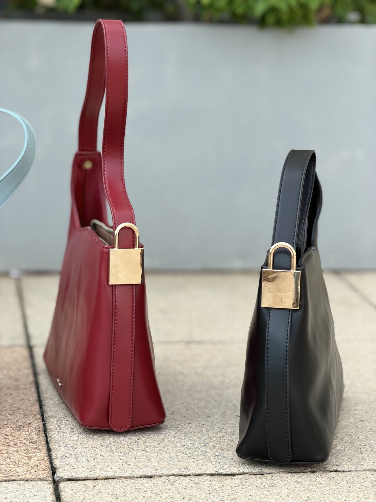 Paired Oriana Gold-Lock Bag in red and black, standing together with gold-tone padlock charms at the side