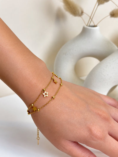 Paired Amavelle Bracelet in gold-tone, worn on the wrist with double chains, beads and an open star charm