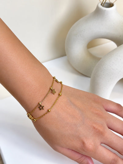 Paired Amavelle Bracelet in gold-tone, worn on the wrist with a layered double chain and open star charm