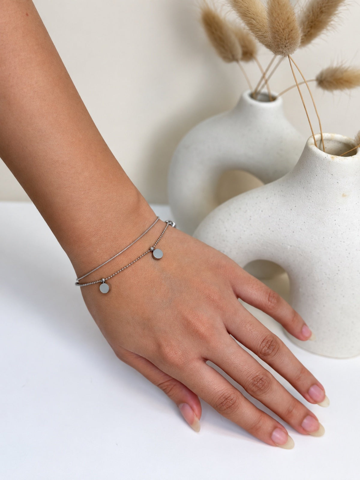 Paired Ariellea Bracelet in silver-tone, worn on the wrist with fine double strands and small round disc charms