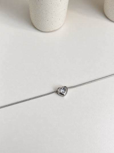 Paired Ariovelle Bracelet in silver-tone, laid flat showing a slim chain and a heart-shaped clear stone