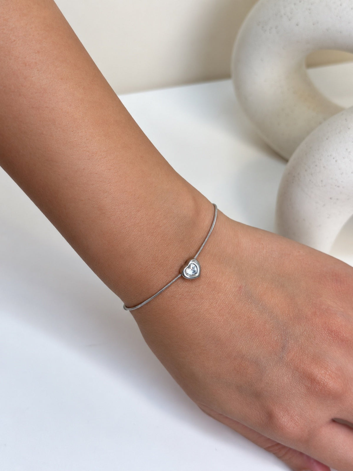 Paired Ariovelle Bracelet in silver-tone, close view on the wrist with a heart-shaped clear stone at the centre