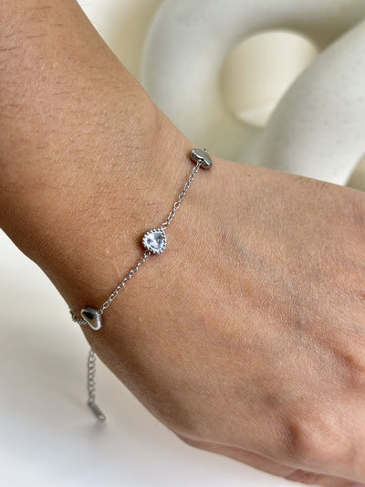 Paired Arlisse Bracelet in silver-tone, close view on the wrist with a heart-shaped clear stone and heart charms