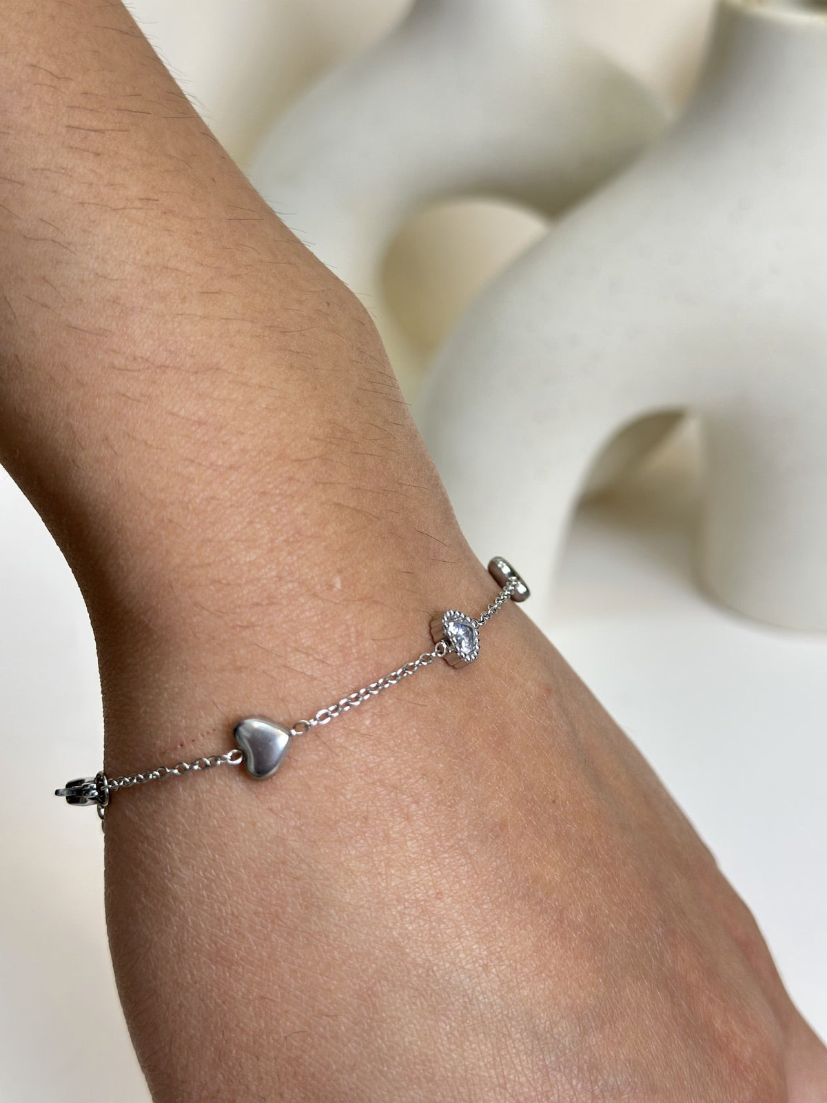 Paired Arlisse Bracelet in silver-tone, close-up on the wrist showing a clear stone and a smooth heart charm