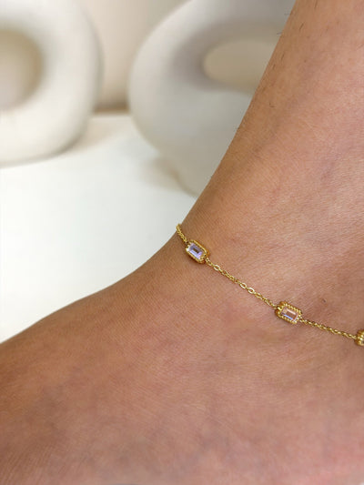 Paired Aveline Anklet in gold-tone, close view on the ankle showing rectangular clear stones on a fine chain