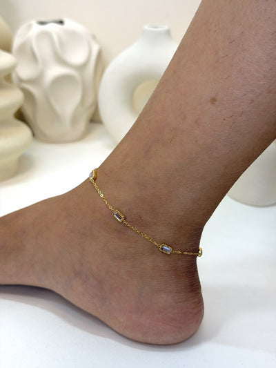 Paired Aveline Anklet in gold-tone, side view on the ankle with evenly spaced rectangular clear stones