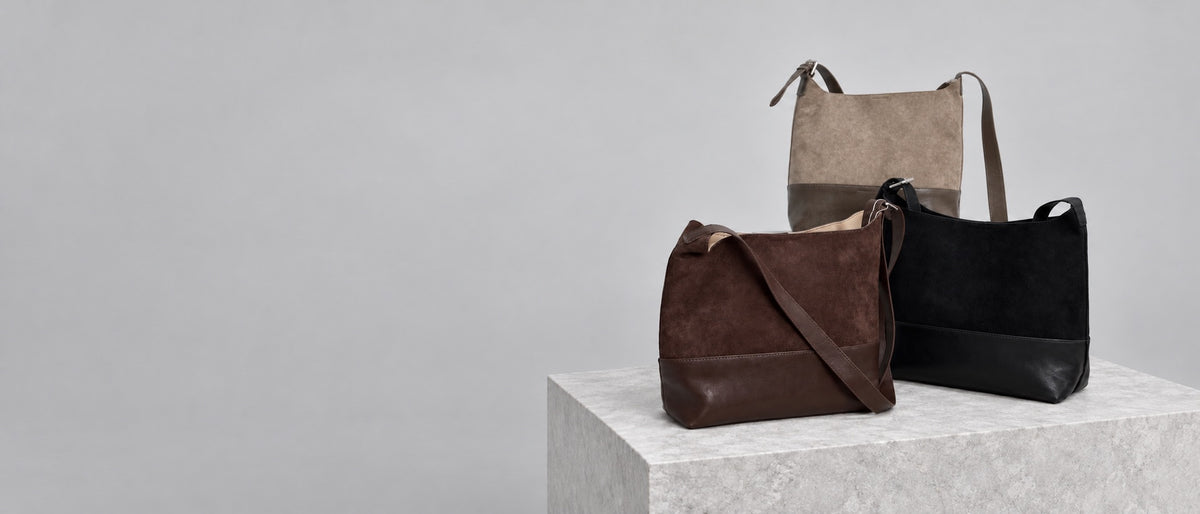 Paired sling bags collection on a stone plinth in a light grey studio