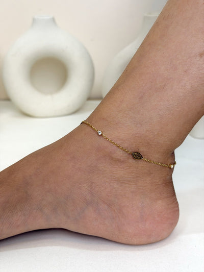 Paired Calisse Anklet in gold-tone, worn on the ankle with a fine chain and a small leaf-shaped charm