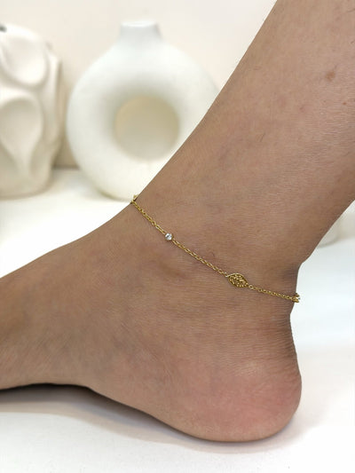 Paired Calisse Anklet in gold-tone, side view on the ankle with a delicate chain and a small leaf charm
