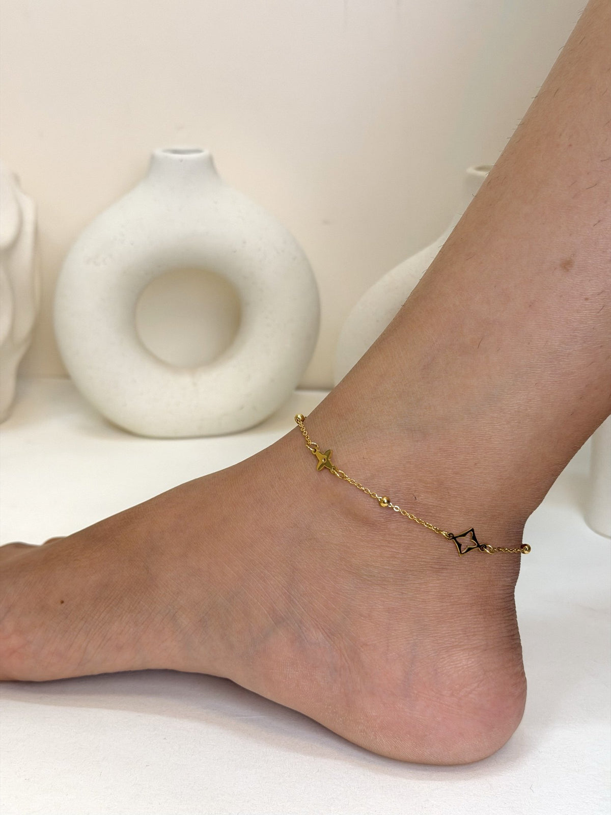 Paired Celeste Anklet in gold-tone, worn on the ankle with a beaded chain and open star-shaped charms