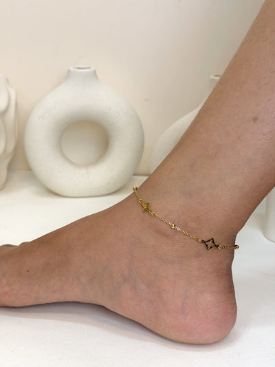 Paired Celeste Anklet in gold-tone, worn on the ankle with a beaded chain and open star-shaped charms