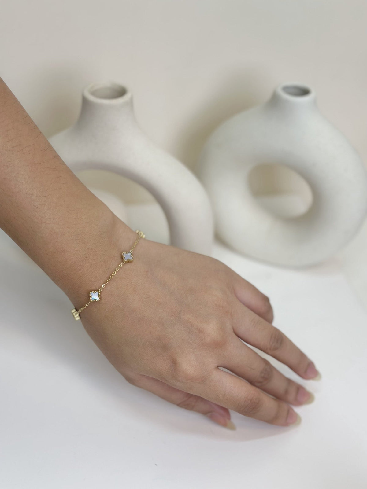 Paired Clover Petite Bracelet in gold-tone, worn on the wrist with a fine chain and small clover-shaped motifs