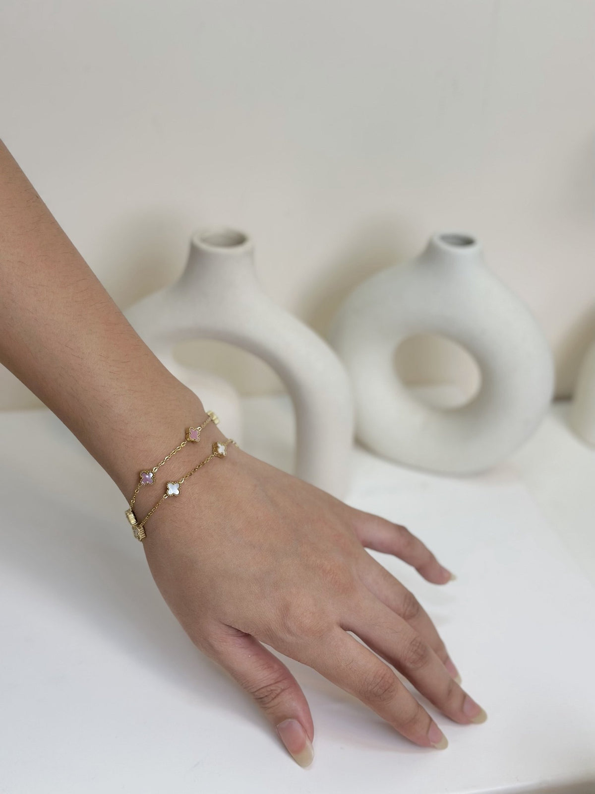 Paired Clover Petite Bracelet in gold-tone, two bracelets stacked on the wrist in different pastel clover tones