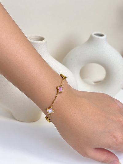 Paired Clover Signature Bracelet in gold-tone, worn on the wrist with pink and white clover-shaped motifs