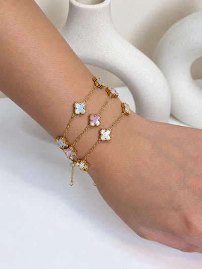 Paired Clover Signature Bracelet in gold-tone, three bracelets stacked on the wrist in pastel clover tones