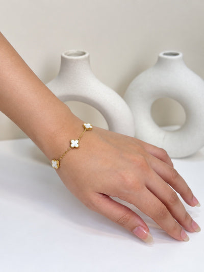 Paired Clover Signature Bracelet in white, gold-tone chain worn on the wrist with clover-shaped motifs