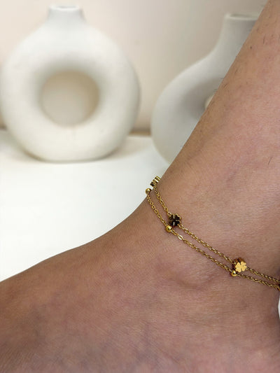 Paired Elara Anklet in gold-tone, close view on the ankle showing double chains and flower-shaped charms