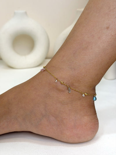 Paired Elarose Anklet in gold-tone, worn on the ankle with a beaded chain and small pink, clear and turquoise drops