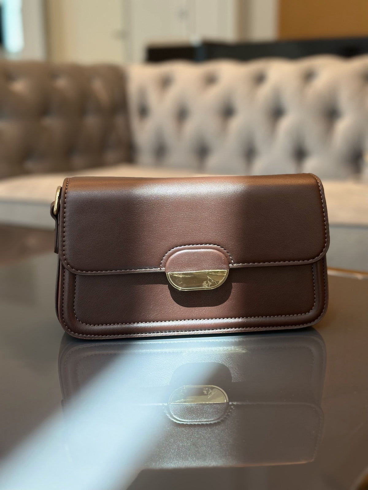 Paired Elise Lock Bag in coffee brown, with a smooth flap and gold-tone half-moon lock plate, standing on a glossy table