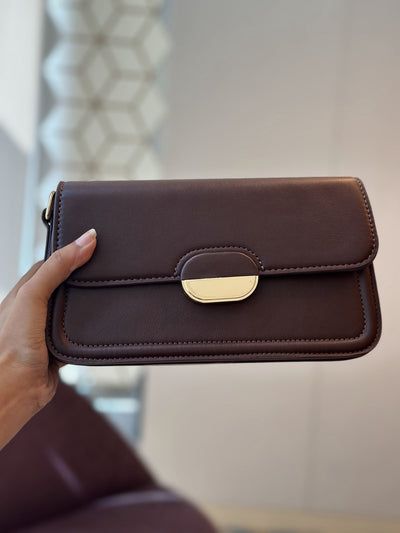 Paired Elise Lock Bag in coffee brown, held in the hand, with a smooth flap and gold-tone half-moon lock plate