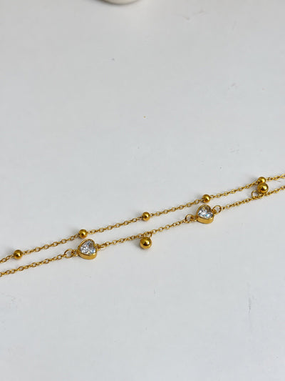 Paired Eliselle Bracelet in gold-tone, flat close-up of the double chain with clear heart stones and round beads