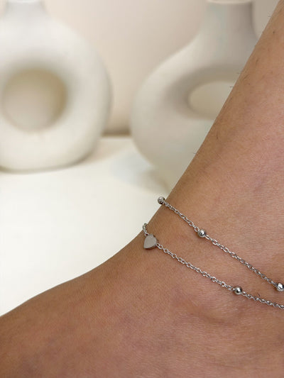 Paired Ella Anklet in silver-tone, close view on the ankle showing a small heart charm and beaded chains