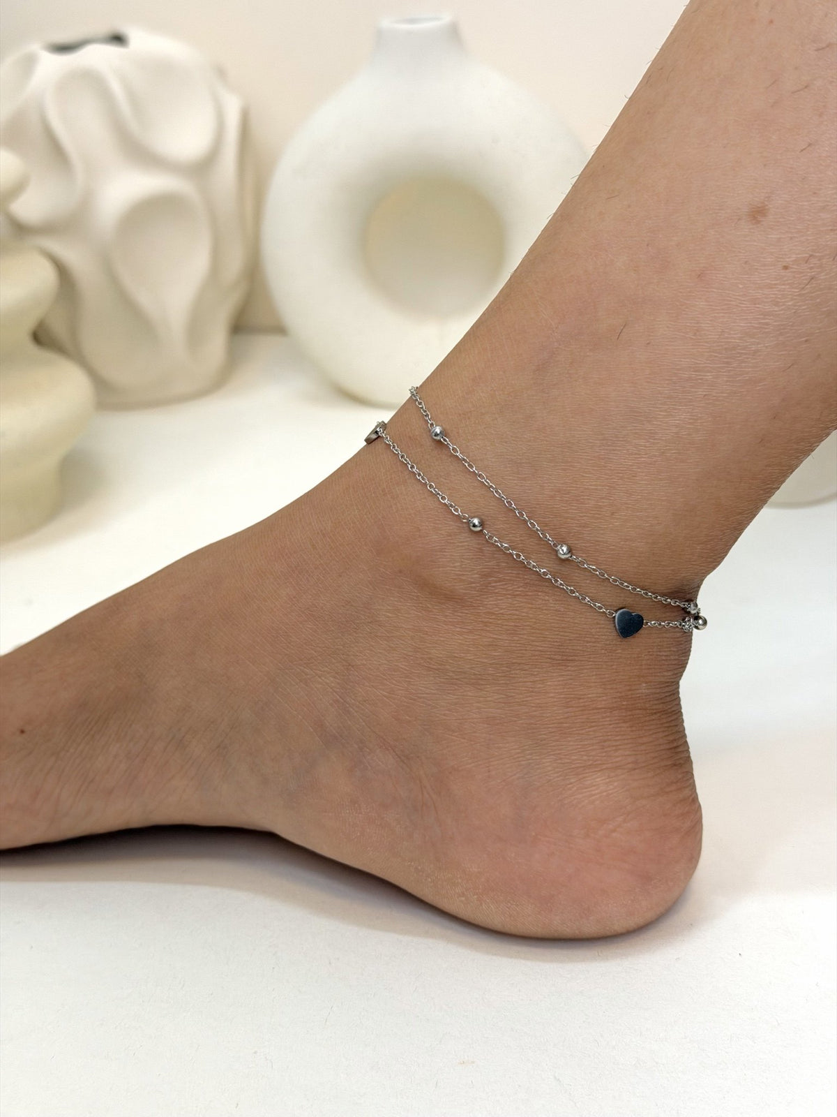 Paired Ella Anklet in silver-tone, worn on the ankle with double beaded chains and a small heart charm