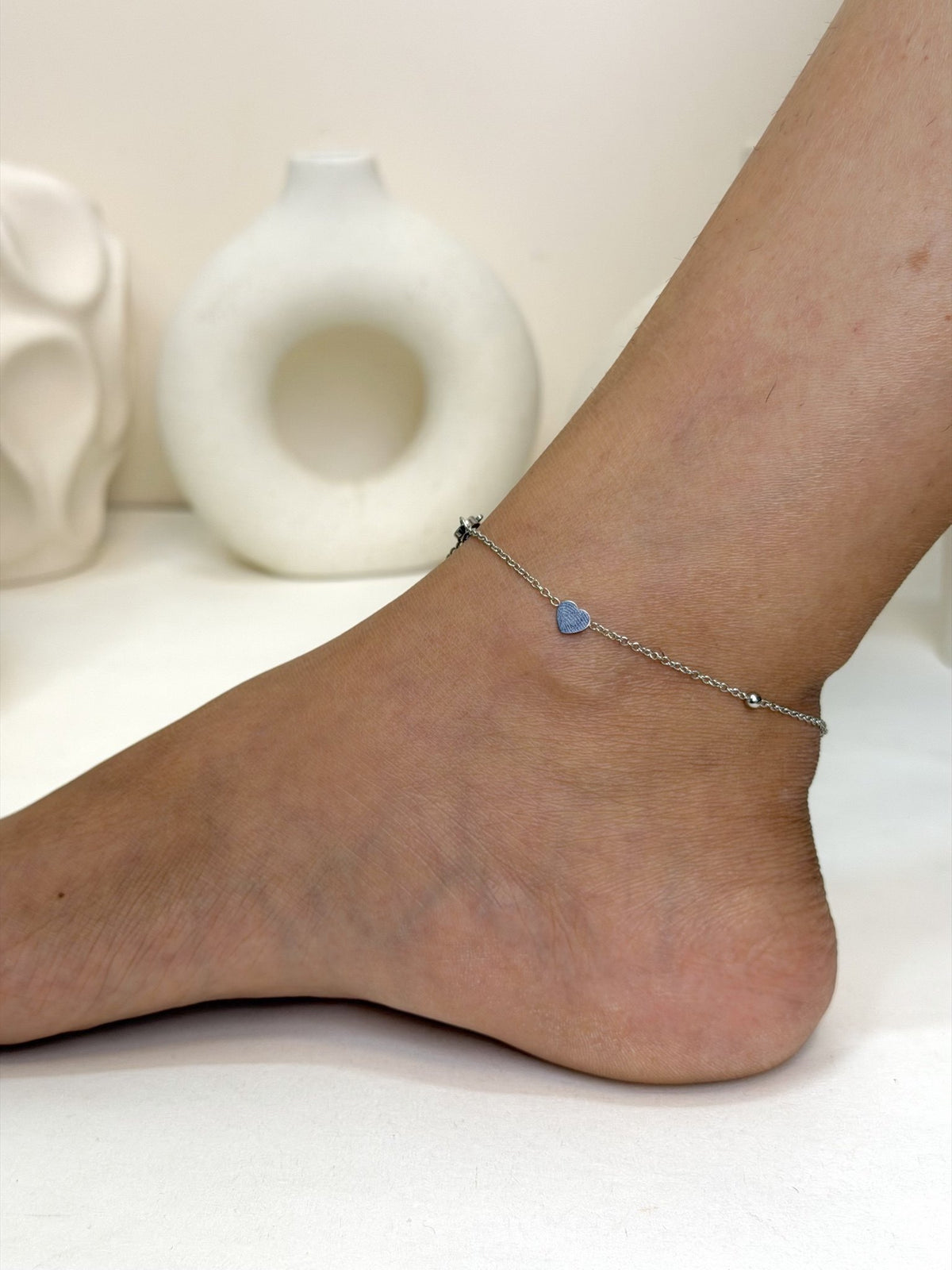 Paired Ella Anklet in silver-tone, side view on the ankle with a fine beaded chain and a small heart