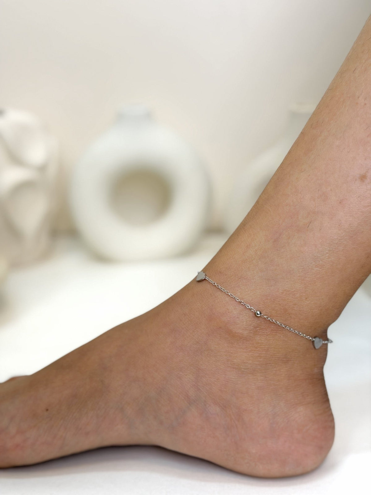 Paired Ella Anklet in silver-tone, worn on the ankle with a fine beaded chain and a small charm