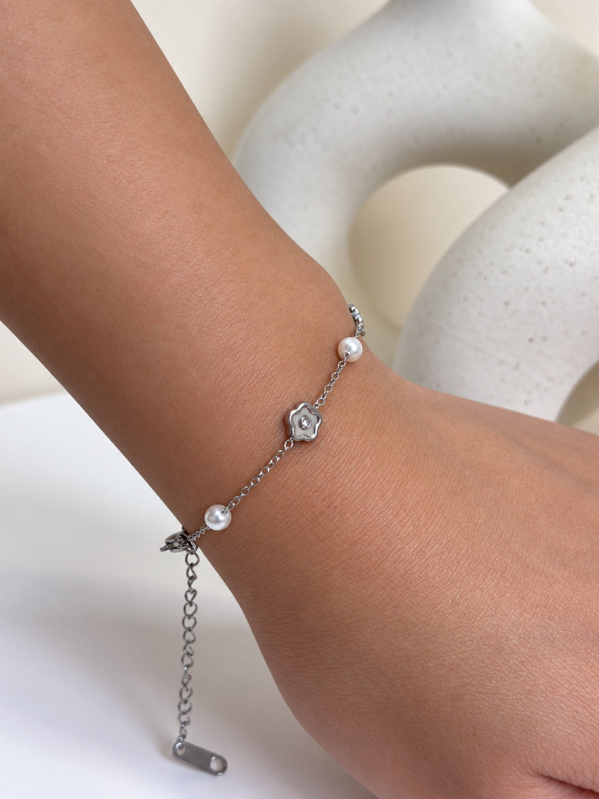 Paired Elowira Bracelet in silver-tone, close view on the wrist showing the clear-stone flower charm and white beads