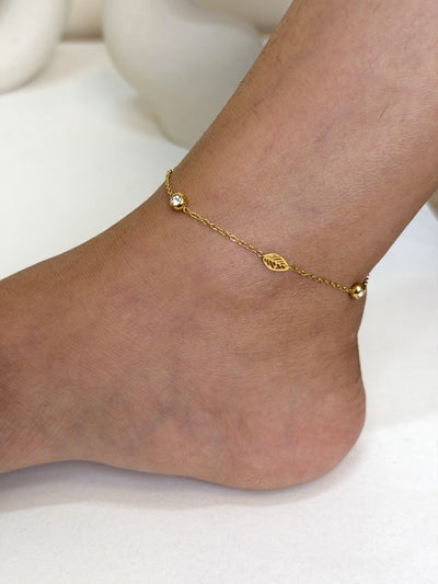 Paired Elvara Anklet in gold-tone, close view on the ankle showing a leaf charm between two small beads