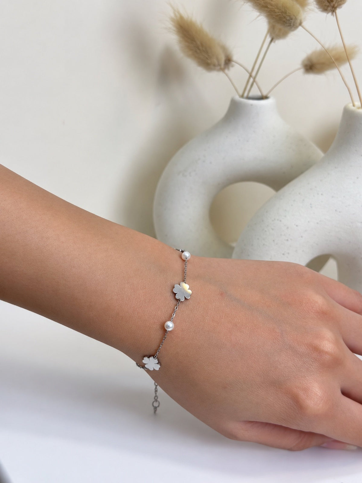 Paired Evelora Bracelet in silver-tone, worn on the wrist with a fine chain, white flower charms and tiny beads