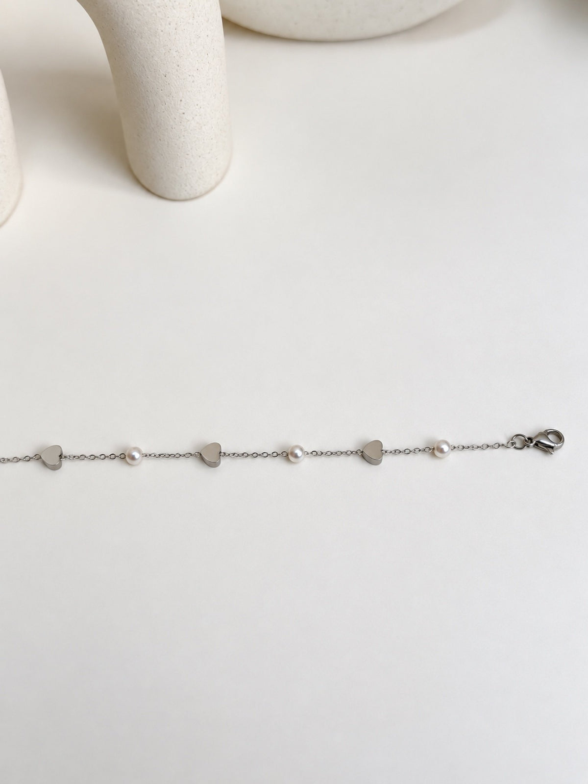 Paired Lavinza Bracelet in silver-tone, laid flat showing alternating hearts and white beads with a lobster clasp