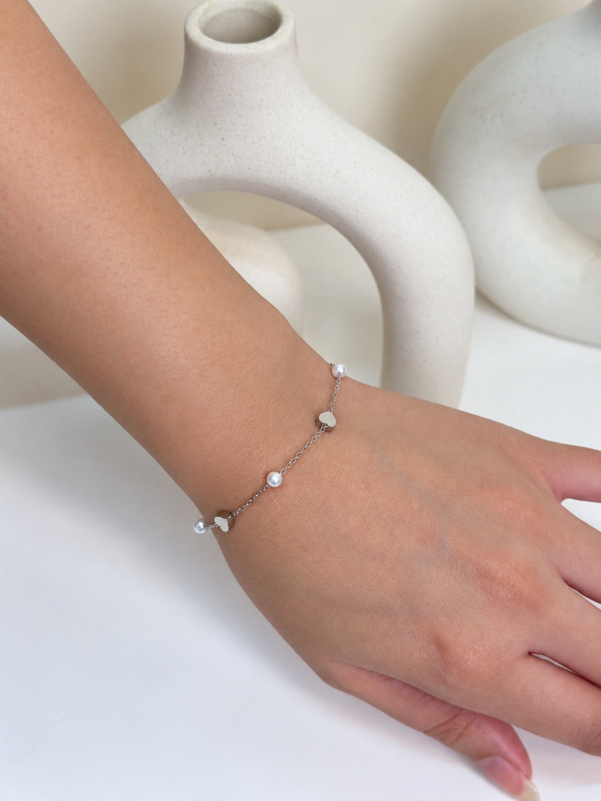 Paired Lavinza Bracelet in silver-tone, close view on the wrist showing heart charms and white beads on the chain