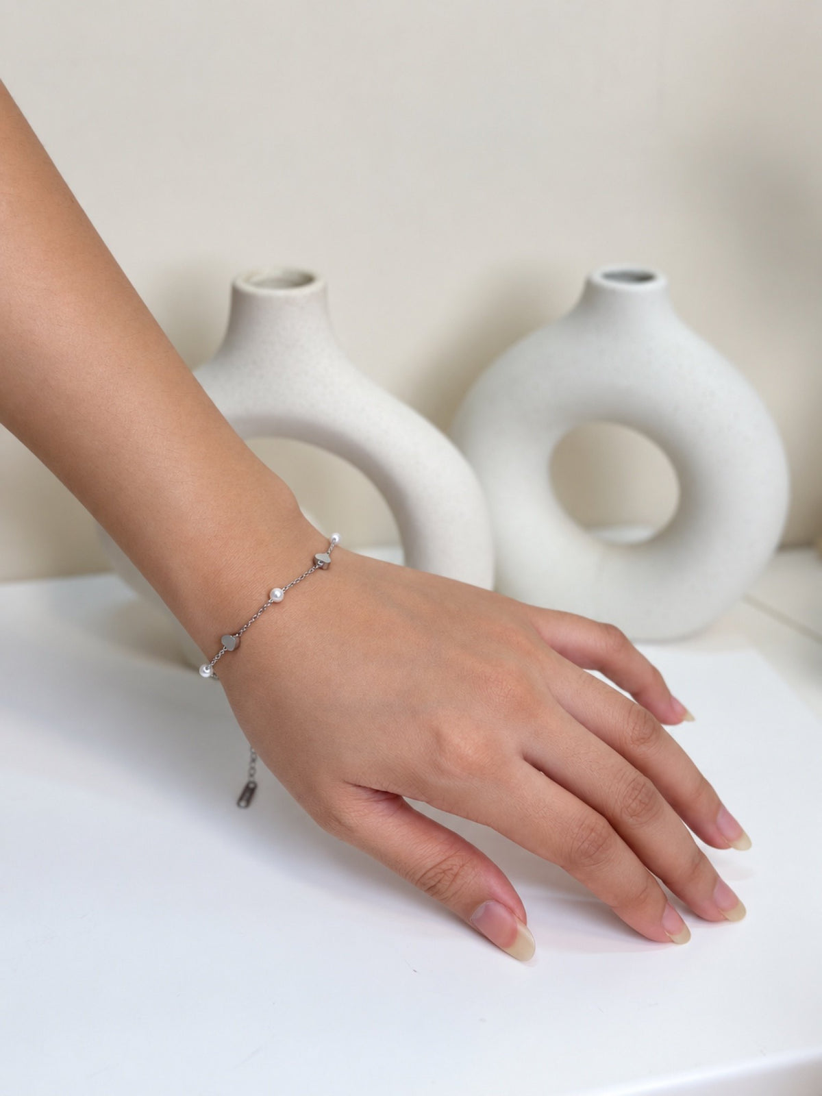 Paired Lavinza Bracelet in silver-tone, worn on the wrist with heart charms, white beads and an adjustable end