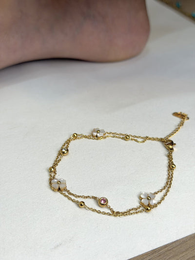 Paired Liora Anklet in gold-tone, laid flat showing double chains, white clover charms, beads and a pink stone