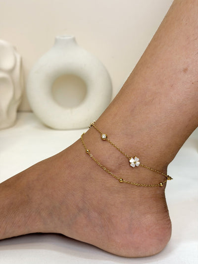 Paired Liora Anklet in gold-tone, worn on the ankle with double chains, a white clover charm and beads