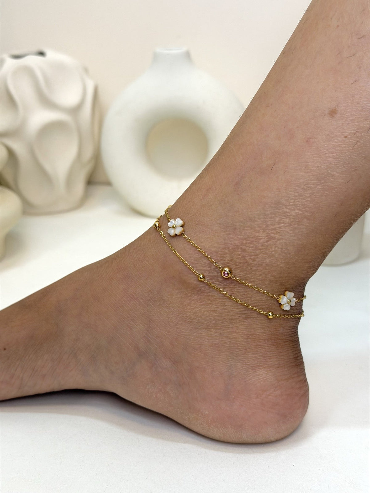 Paired Liora Anklet in gold-tone, side view on the ankle with layered chains and clover-shaped charms