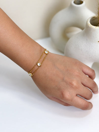 Paired Lisandra Bracelet in gold-tone, worn on the wrist with two fine chains and round clear stones