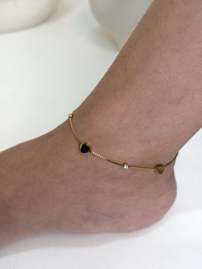 Paired Lorielle Anklet in gold-tone, close view on the ankle with heart charms and small clear stones