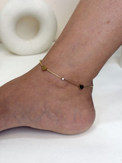 Paired Lorielle Anklet in gold-tone, side view on the ankle showing heart charms along the fine chain